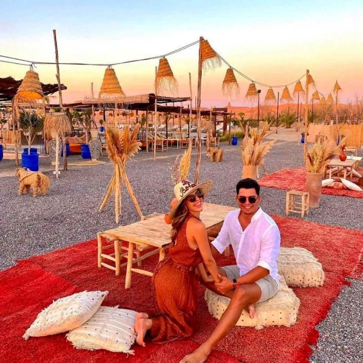 Couple sitting on Berber rugs in the desert camp lounge at golden hour