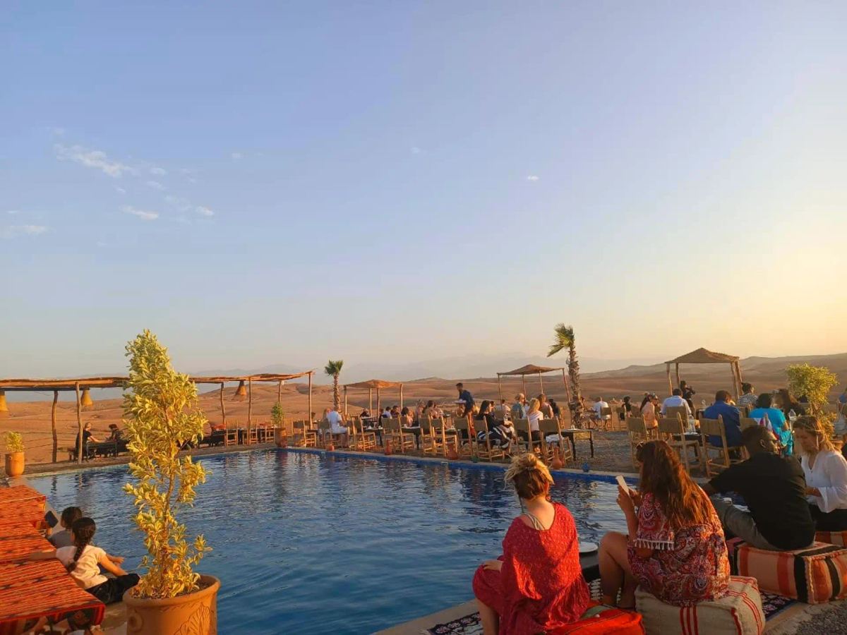 Guests relaxing by the desert camp pool with views of the Agafay hills