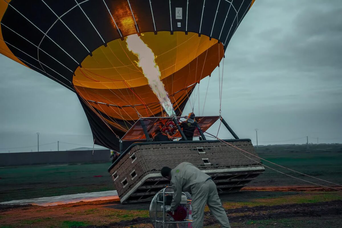 Crew inflating a hot-air balloon with the burner before dawn