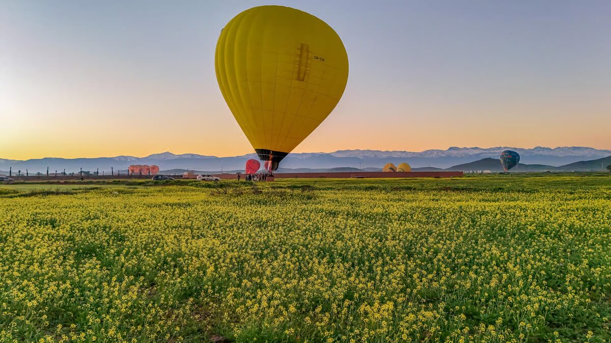 Yellow balloon above green fields with the Atlas Mountains in the distance
