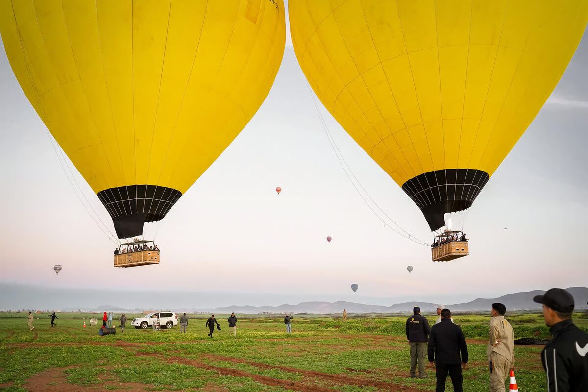 Two yellow hot-air balloons lifting off from a field near Marrakech