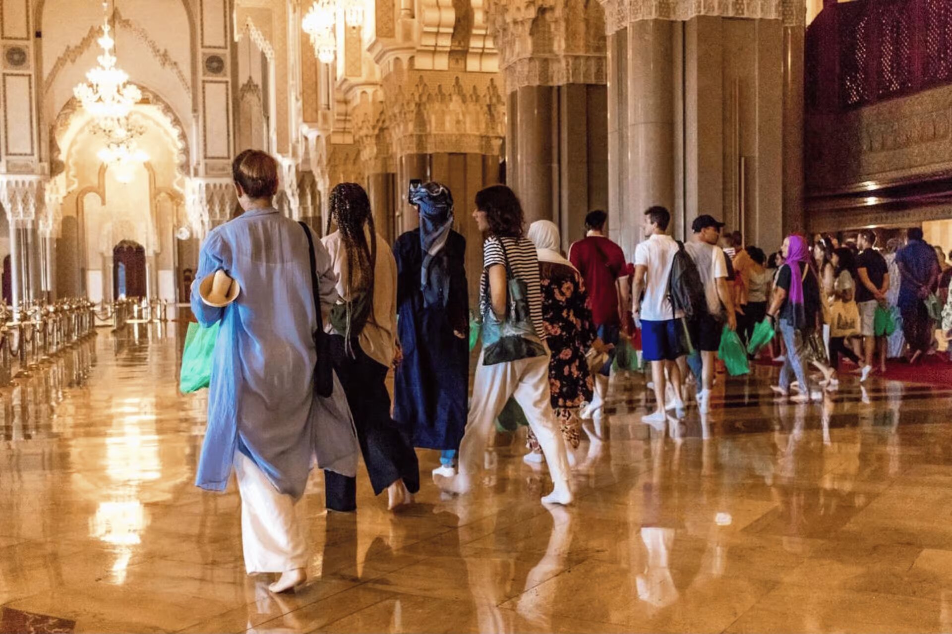 Visitors walking across the polished marble floor inside the Hassan II Mosque
