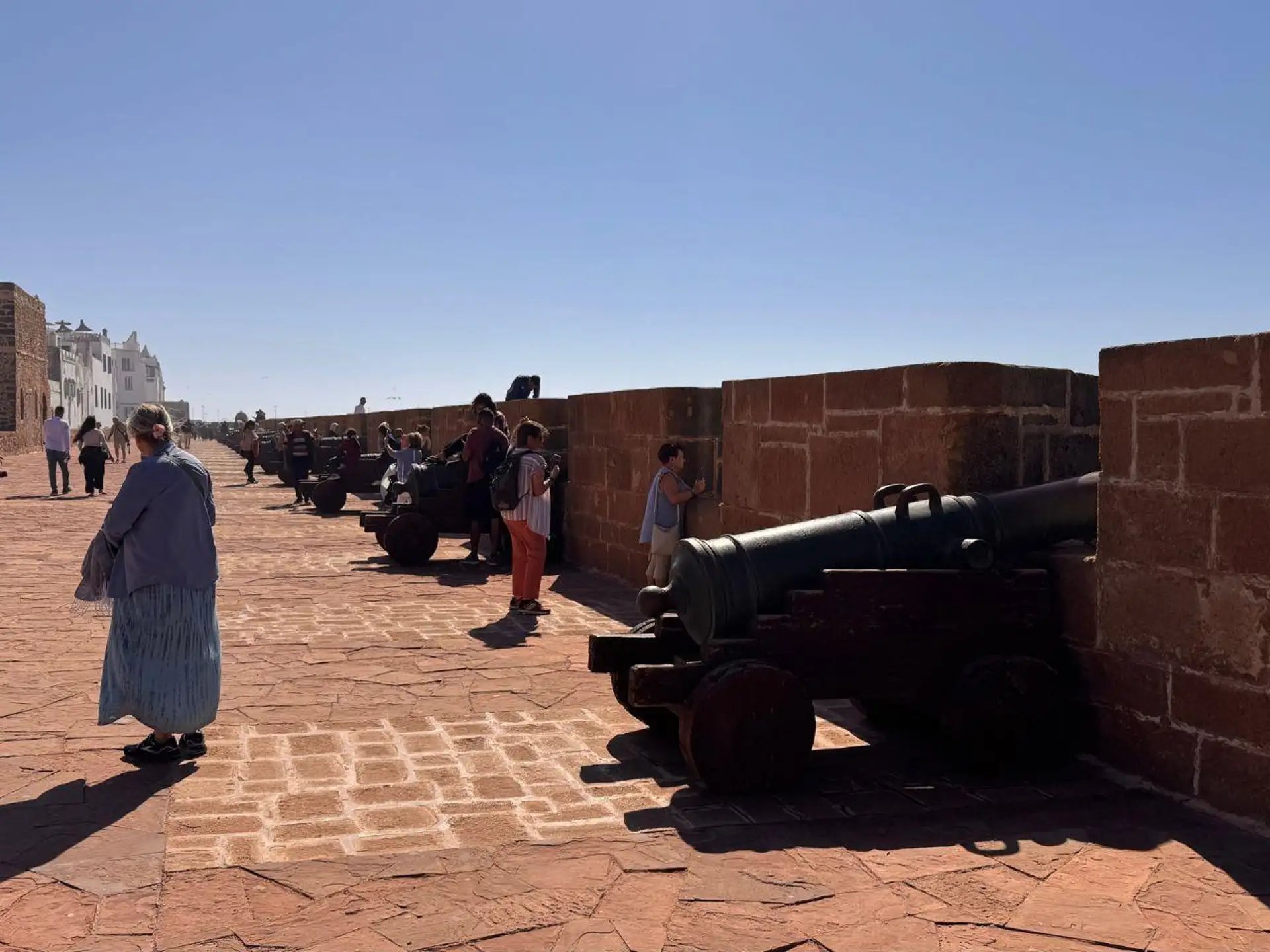 Visitors walking along the row of old cannons on Essaouira's sea walls