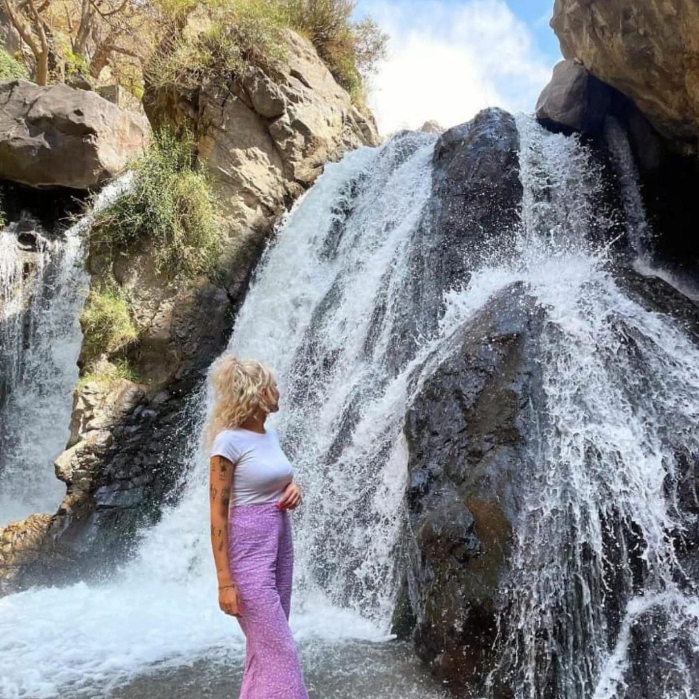 Traveler admiring a powerful waterfall pouring over dark rocks