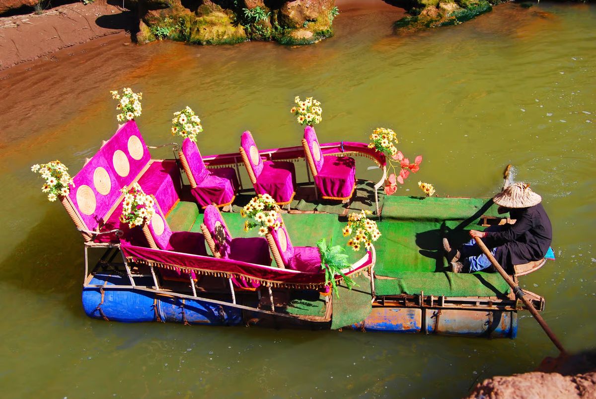 Boatman rowing a colorful flower-decorated boat on the river at Ouzoud