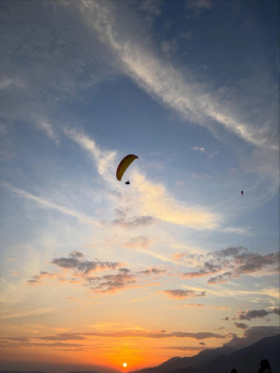 Paraglider silhouetted against a golden sunset sky
