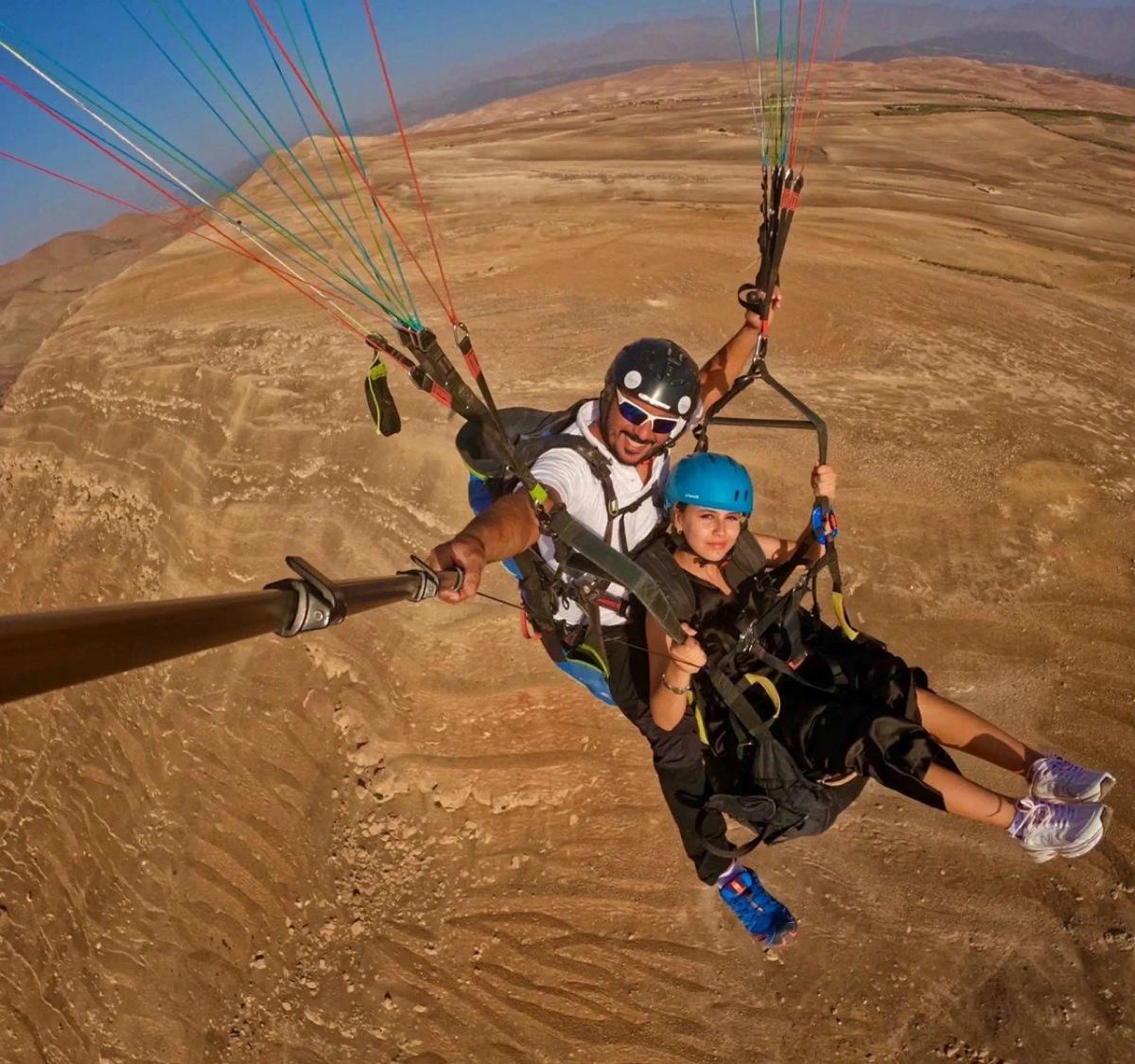 Tandem paraglider and passenger flying high above the Aguergour hills