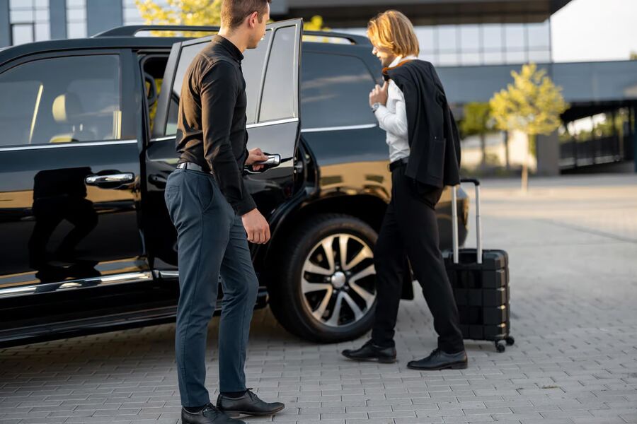Driver opening the car door for a traveler with luggage