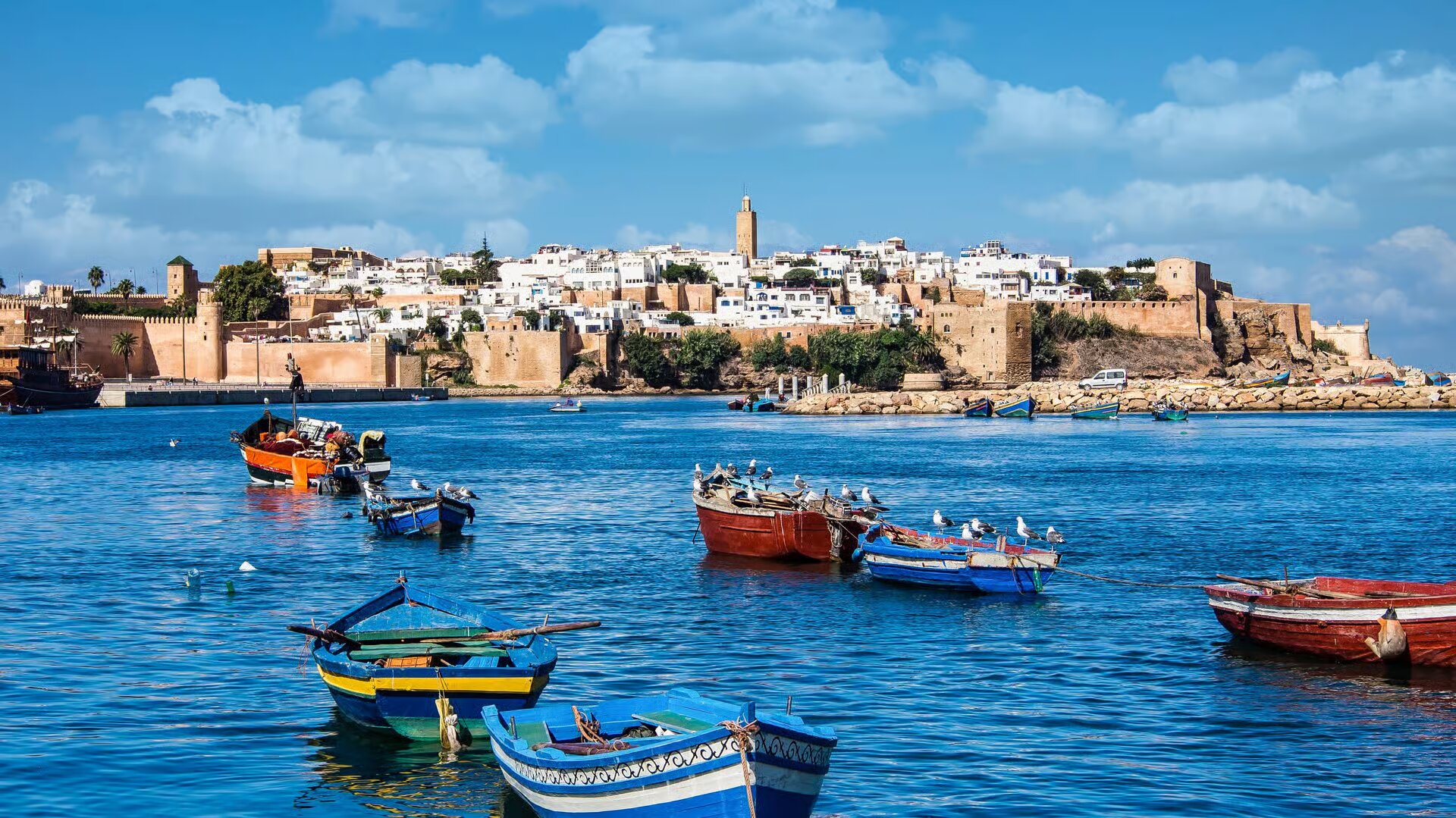 Colorful fishing boats on the Bouregreg River below the white houses of the Kasbah of the Udayas